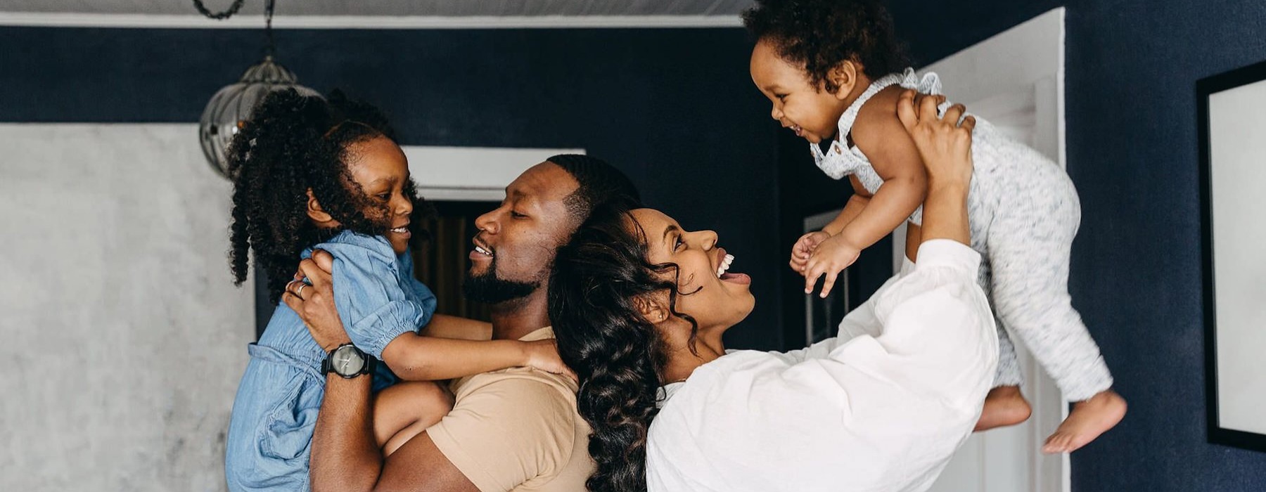 young parents hold up their children in room